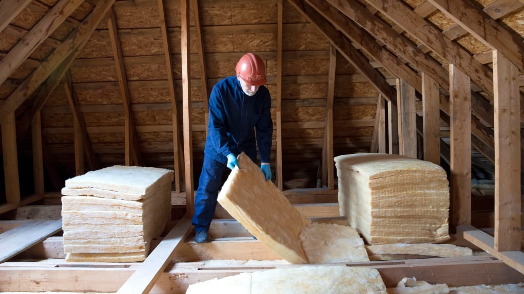 A specialized worker installing roof insulation in a house