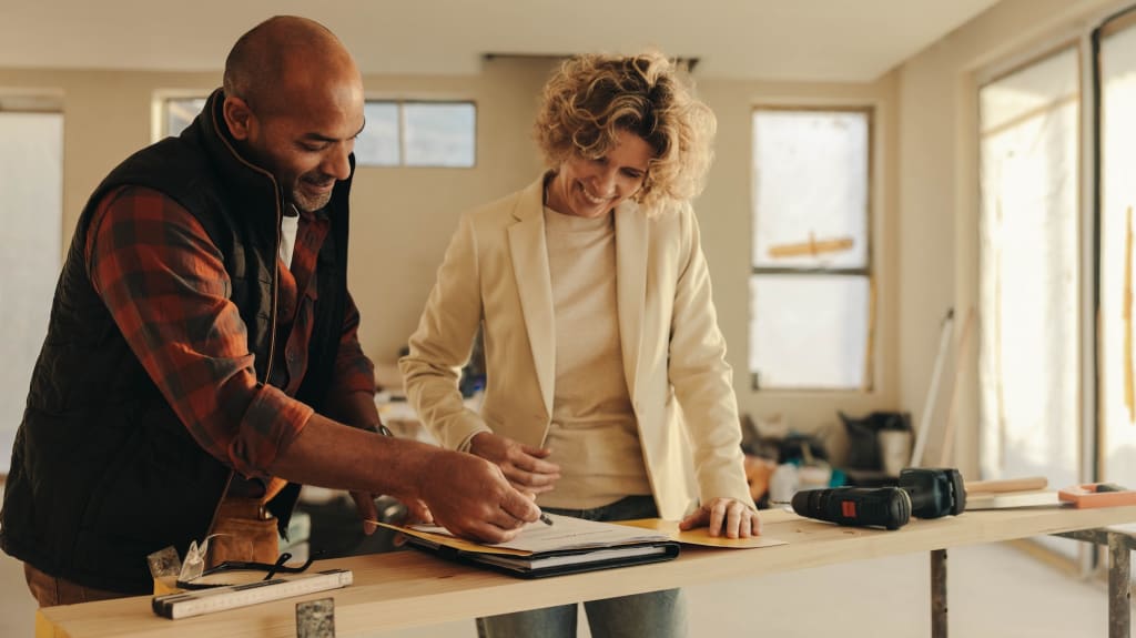 A contractor studies plans with a homeowner before getting renovations started