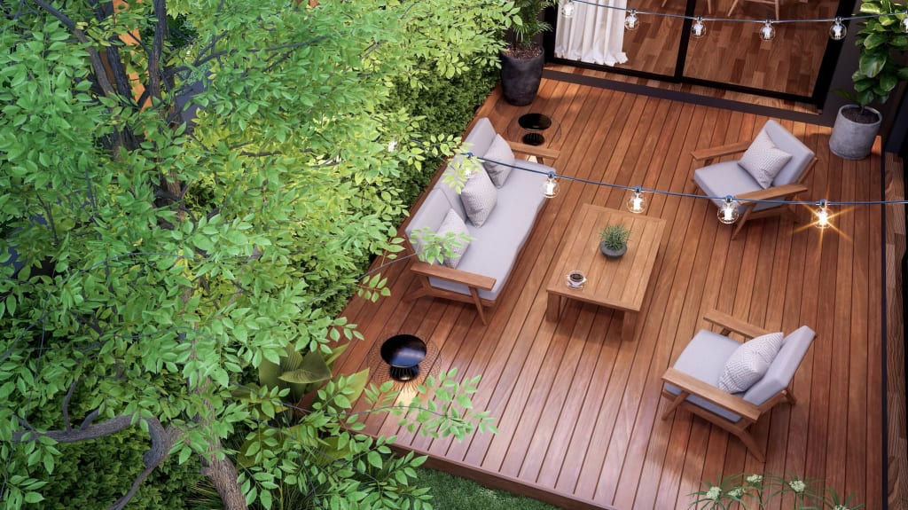 Aerial view of a backyard with wooden deck, outdoor furniture and large overhanging tree.