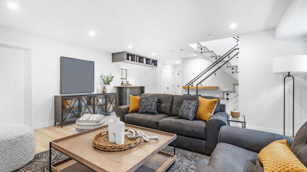Basement living room with grey sofas, yellow cushions and a wooden coffee table