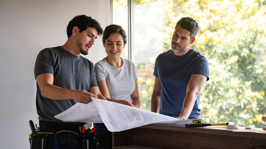 Propriétaire consultant ses plans avant de demander un permis de rénovation.