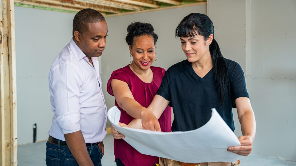 Couple regardant des plans de maison avec une entrepreneure.