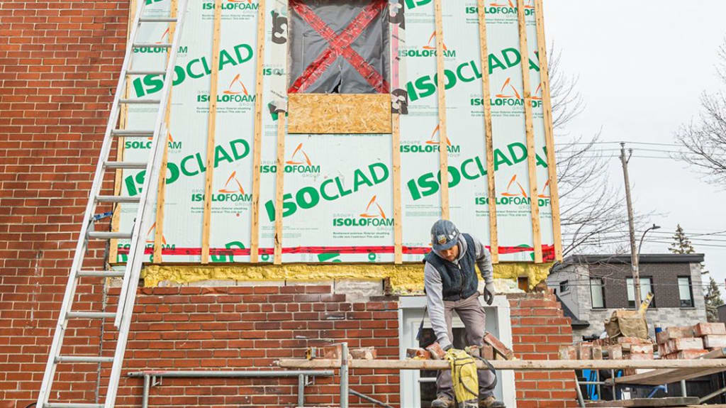 maçon refait un mur de briques sur un immeuble résidentiel