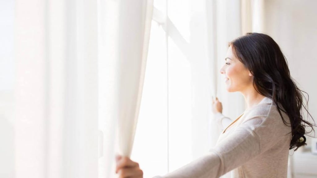 women opening curtains and looking out the windows