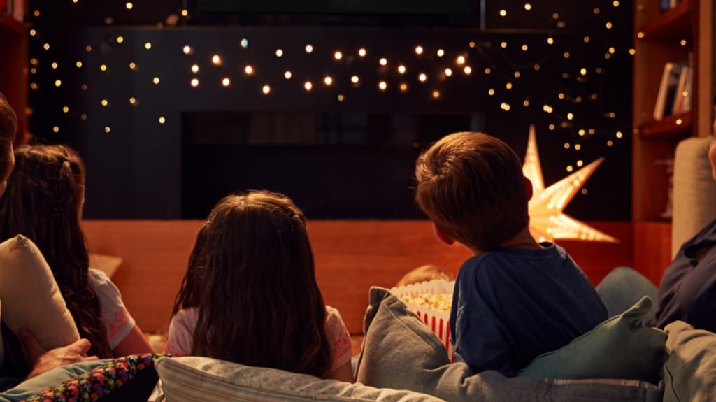 family watching movie from a pile of pillows on the floor