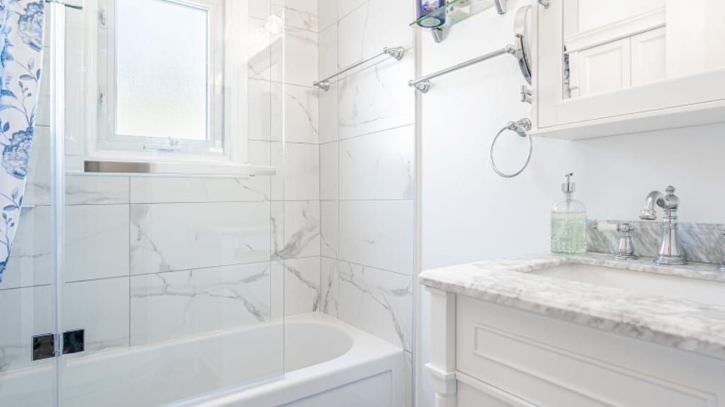 Salle de bain classique blanche avec vue sur baignoire et douche de céramique blanche et comptoir de quartz blanc