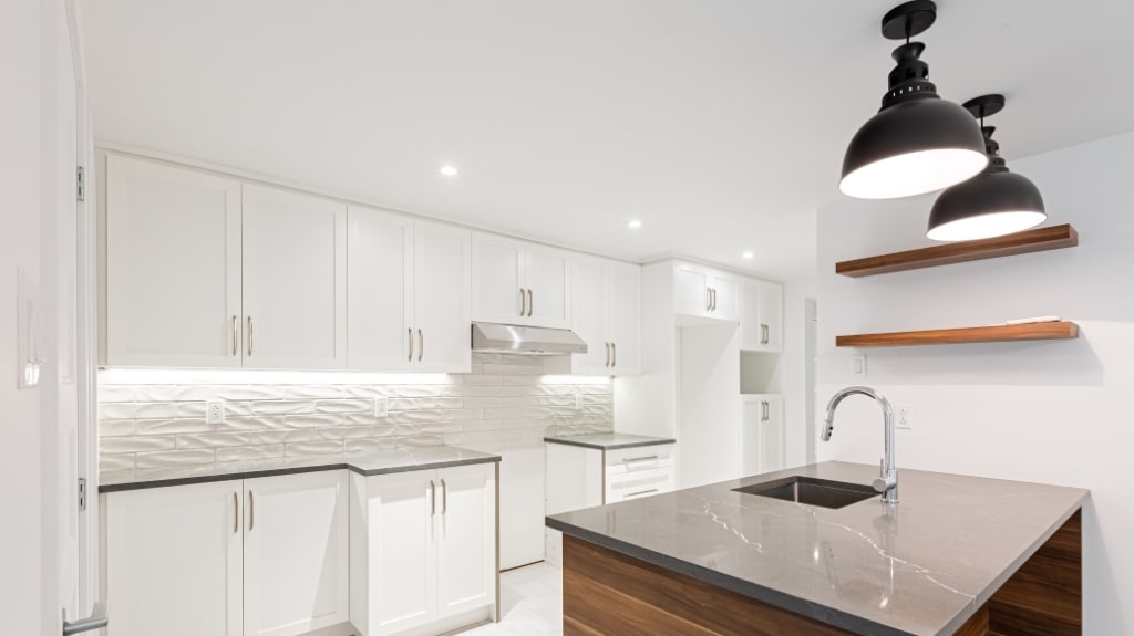 Modern white basement and kitchen, white cabinets with white ceramic backsplash, and island with black quartz countertop
