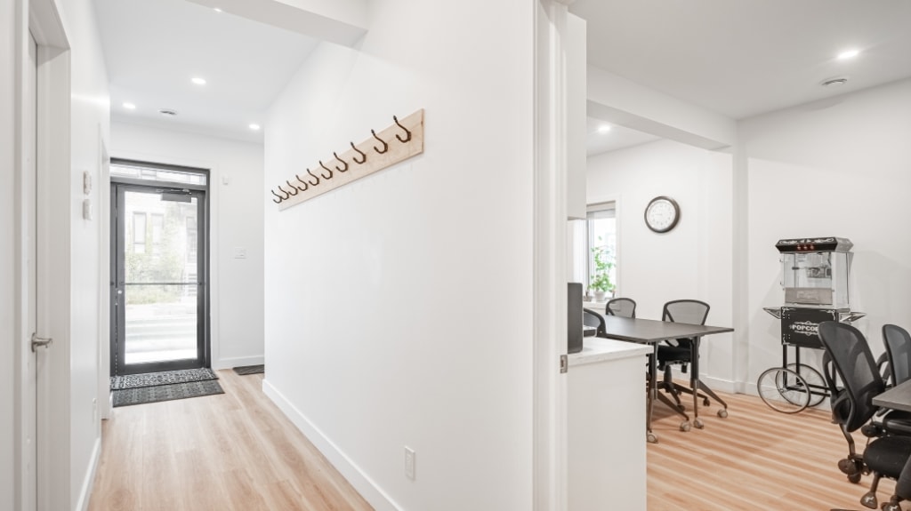 Modern office design featuring bright entryway with white walls and black furniture.