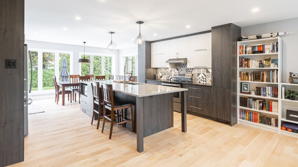 renovated modern kitchen with large windows, bookshelf, and black cabinets