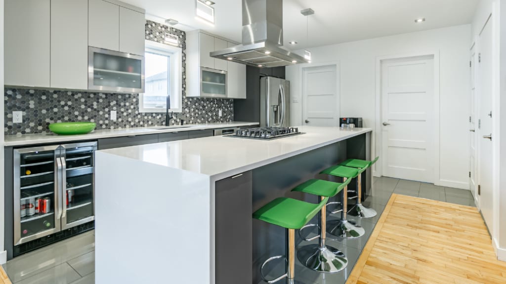 kitchen island with cascading quartz countertop, green stools and hexagonal mold backsplash in a modern kitchen makeover
