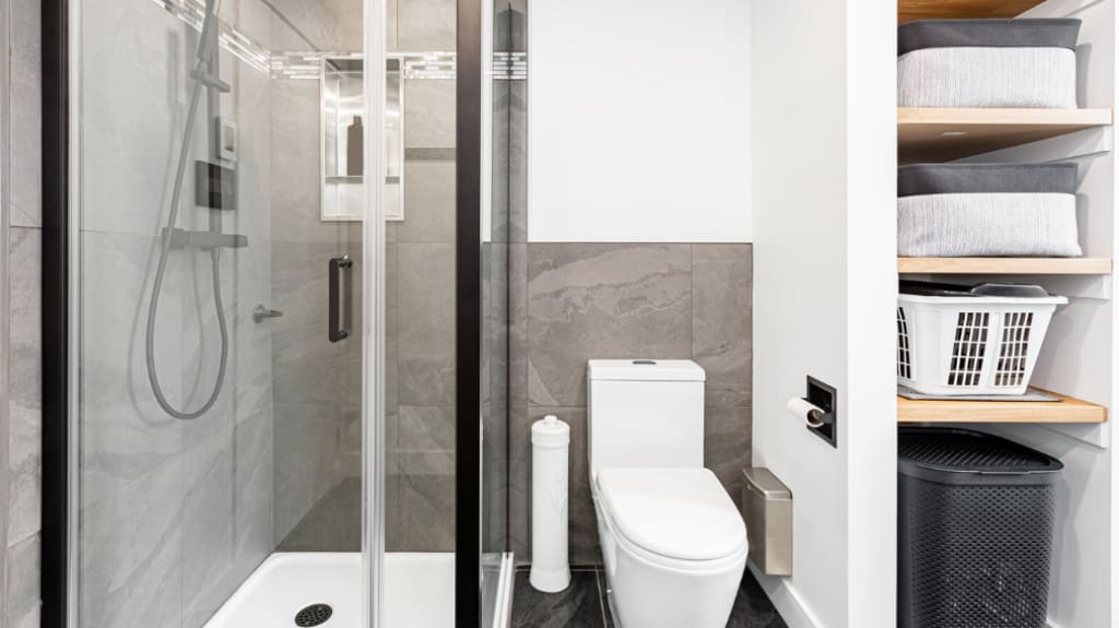 Toilette, douche et tablettes en bois dans une salle de bains rénovée