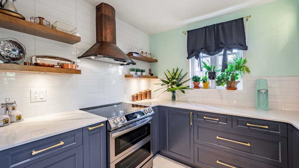 Cuisine bleue et blanche avec un mur vert menthe et des touches de cuivre