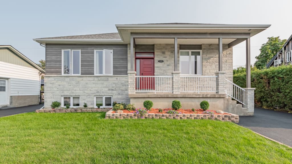 A grey stone single family home with a bright red door