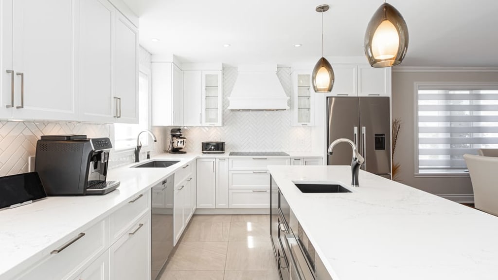 Une cuisine blanche moderne avec îlot et appareils électroménagers en acier inoxydable