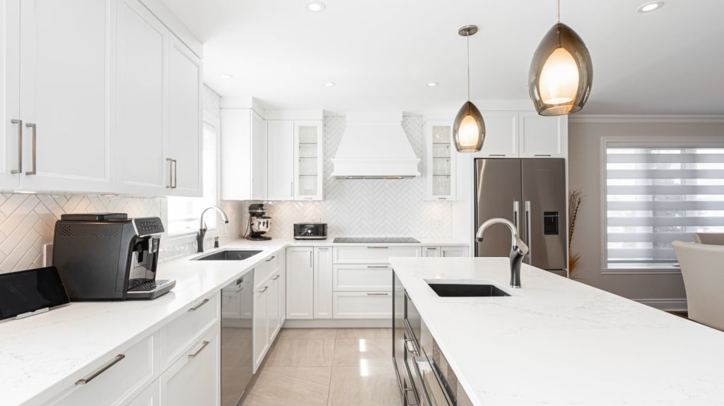 A modern white kitchen with island and stainless steel appliances