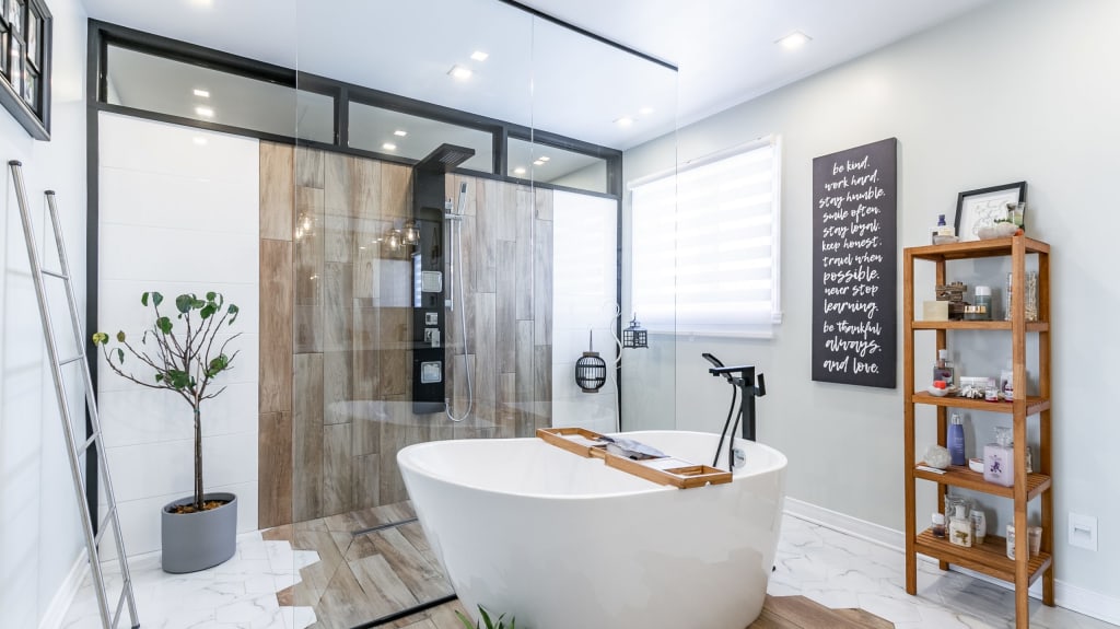 Behind a large glass panel is a walk-in shower with sections of white and wood tiles.