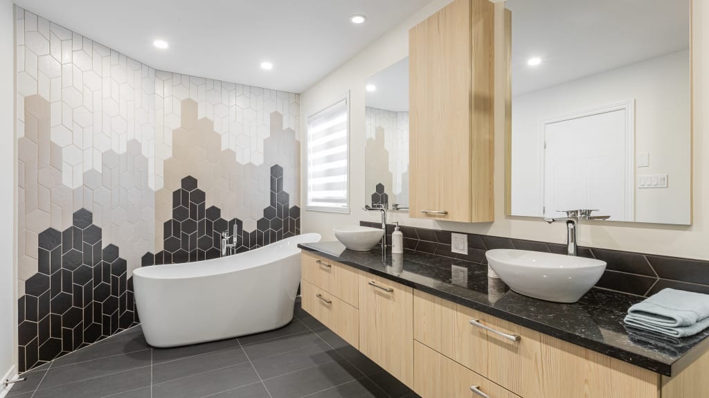 salle de bain rénovée de style moderne avec baignoire autoportante, mur de tuiles géométriques et grande vanité