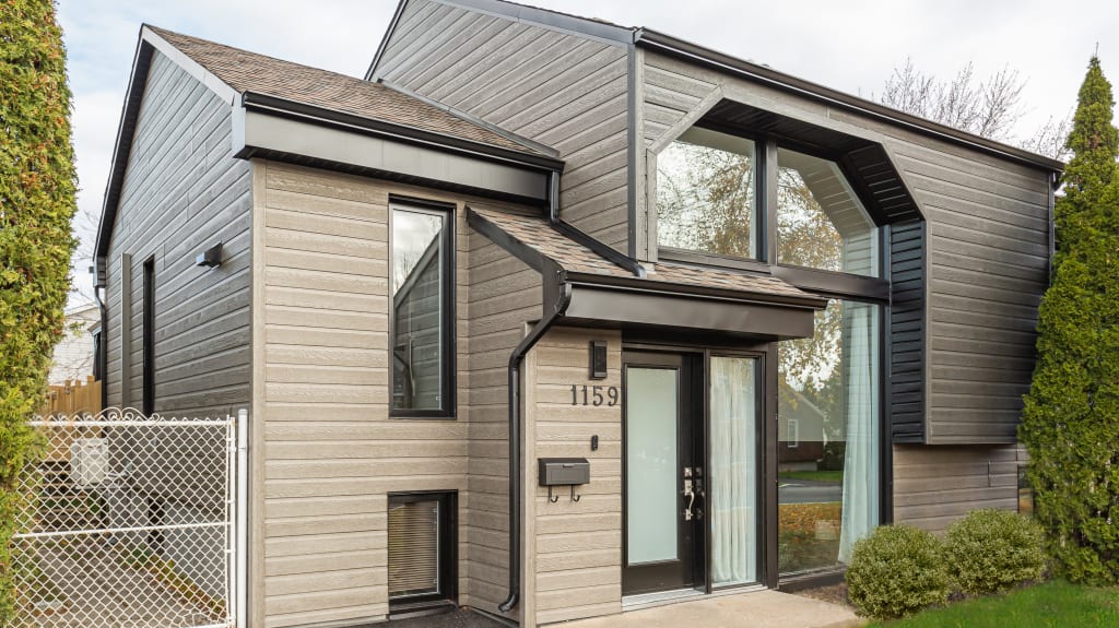 brand new Canexel siding of a bungalow with black doors and windows