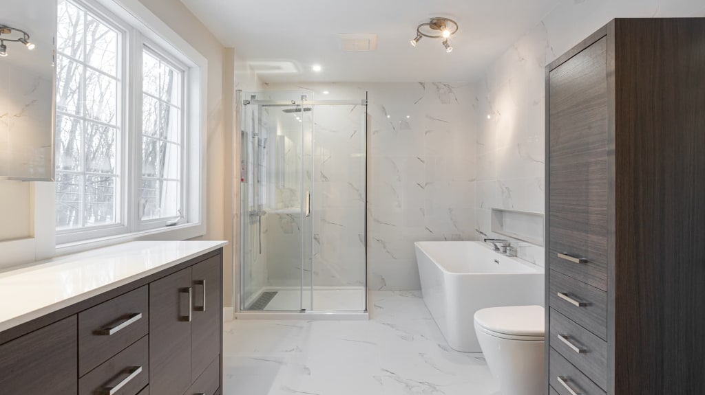 modern bathroom with walk-in shower, marble tiles, dark vanity