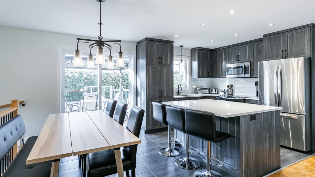 cuisine moderne avec armoire gris foncé et îlot avec coin lunch et bancs