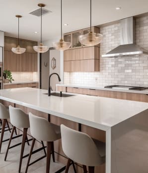 Modern grey kitchen with wood cabinets and four glass pendant lights