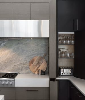 Stainless steel hood and oven in a gray and black kitchen