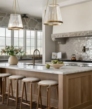 Kitchen with stone wall and large windows, two light fixtures in the form of glossy lampshades, wide hood and large island 