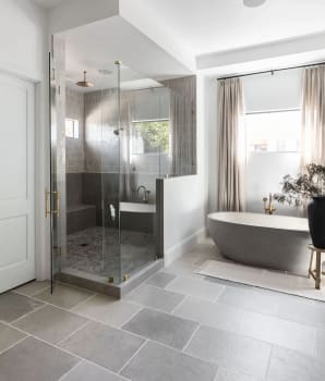 Deux modèles de tuiles grises sur le plancher d’une salle de bain et le sol de douche