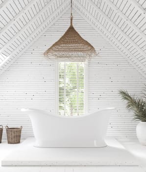 Baignoire blanche sur podium et luminaire suspendu en rotin