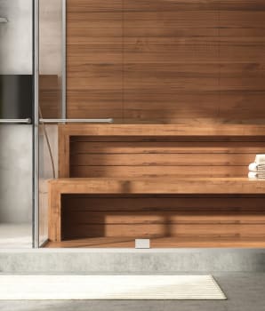 Sauna moderne en bois et douche en verre dans une salle de bain au sol en ciment poli