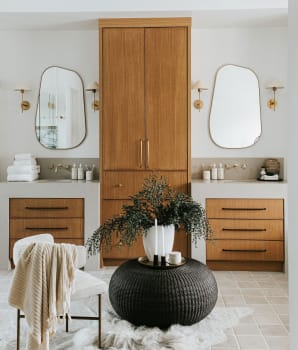Vasques séparées par une armoire en hauteur dans une salle de bain avec miroirs aux formes irrégulières