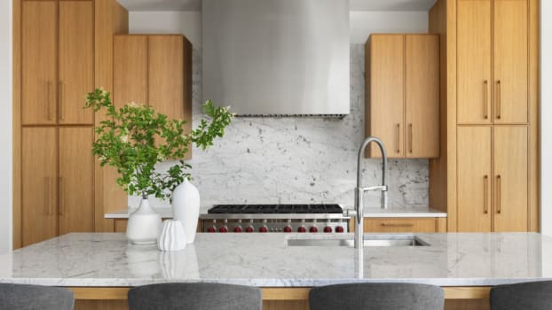 Large stainless steel hood framed by wooden cabinets 