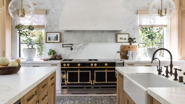 Plaster hood above a vintage stove in a double island kitchen with globe lights