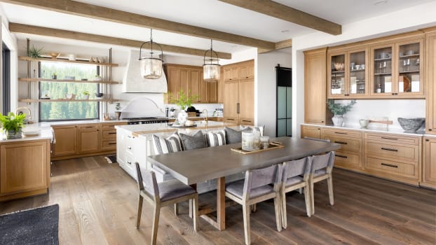 European farmhouse-style kitchen with large dining table, exposed beams and glass cabinet