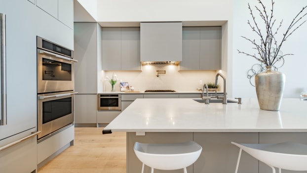 Light grey cabinets, stainless steel fittings, white worktops and benches