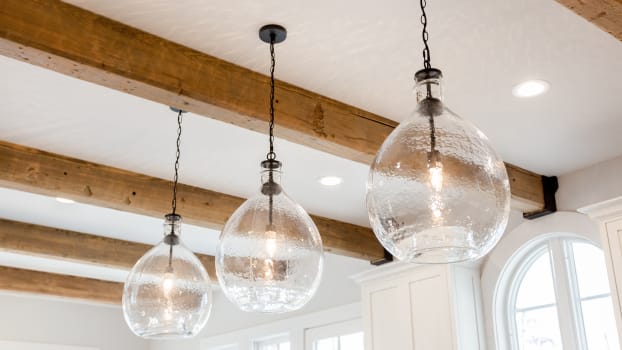Trio of glass luminaires suspended from a ceiling decorated with wooden beams