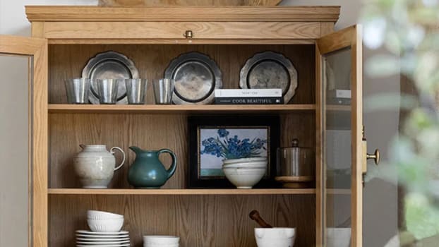 Wooden glass cabinet with pots, plates, frames, glasses and books
