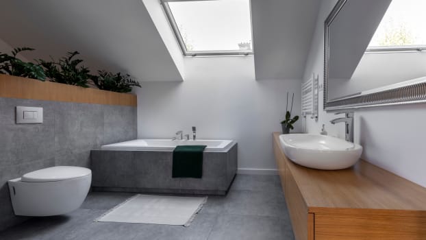 Meuble-vanité en bois, dalles de céramique de couleur grise et puits de lumière dans une salle de bain