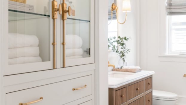 Étagère de salle de bain aux poignées dorées avec accessoires sur étagères