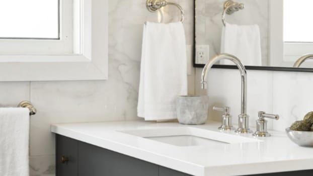 Porte-serviette et robinetterie argentés dans une salle de bain avec petit meuble-lavabo foncé