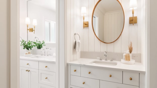 Miroir ovale sur mur de lambris blanc dans une salle de bain ayant deux lavabos