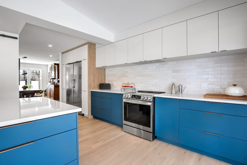 Kitchen with teal and white cupboards, and white backsplash