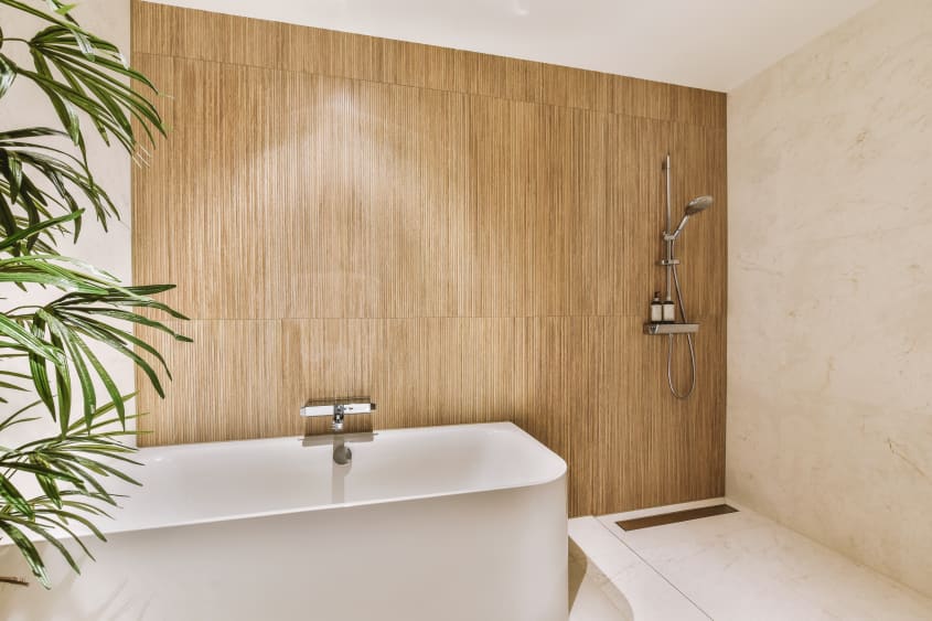Douche, bain et mur accent en bois dans une salle de bain zen à l’éclairage diffus