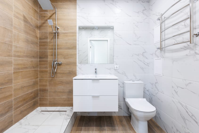 Douche en bois dans une salle de bain aux murs recouverts de céramique blanche à veinures grises