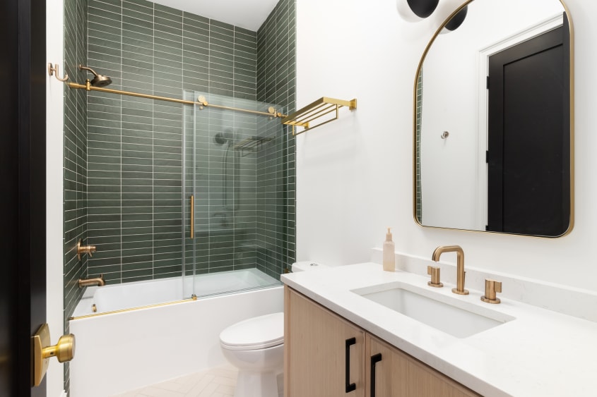 Bain-douche aux contours dorés et mur en céramique avec tuiles horizontales vertes