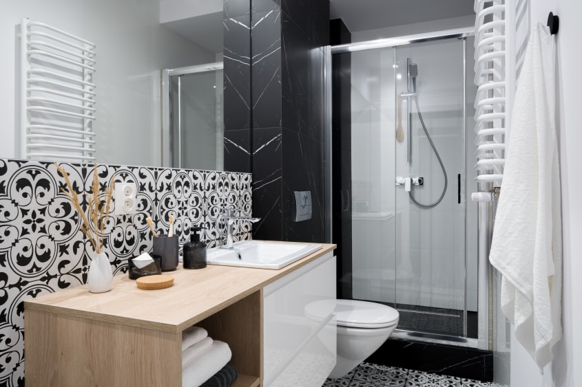 Douche traditionnelle avec porte dans une salle de bain au dosseret à motifs noir et blanc