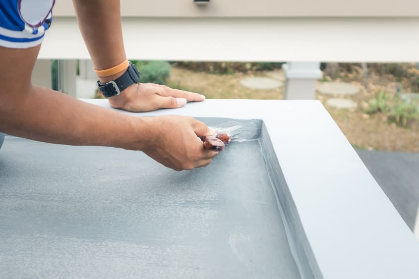 Close up of a person’s hands while painting a deck