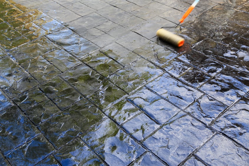 Close up view of concrete floor with a roller brush applying varnish