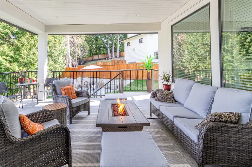 Spacious covered deck with wicker patio furniture and a tabletop fire