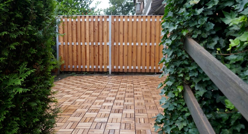 Empty outdoor terrace with mosaic flooring wooden tiles, wooden partition and ivy plants